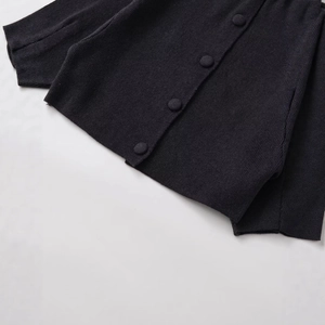 Gilet en tricot gris foncé avec boutons recouverts montrant la patte et l'ourlet