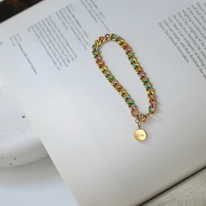 Rainbow enamel chain bracelet with gold-plated lucky coin pendant on art book