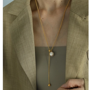 Detail der verstellbaren goldenen Schlangenkette mit Perlen auf einem beigen Blazer