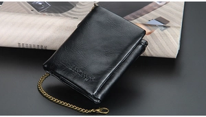 Detail of black leather wallet with vintage metal chain and embossed brand logo on side