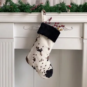 Close-up of plush cow print Christmas stocking hanging on a white festive mantel