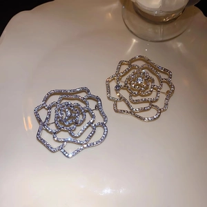 Luxurious gold and silver rose brooches with zircon crystals in a ceramic tray