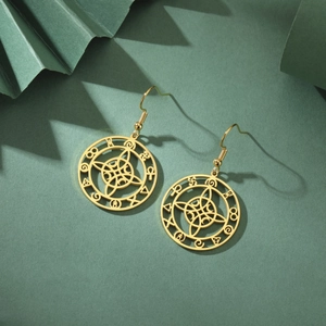 Goldene Edelstahlohrringe mit mystischem Mondanhänger auf elegantem grünem Grund