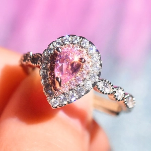 Elegant rose gold halo ring featuring a pear-cut pink stone and sparkling pavé accents