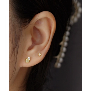 Golden 925 sterling silver heart earrings with sparkling zircon on a model's ear