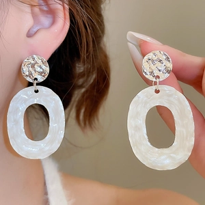 Detail of silver hammer-textured stud with white pearlescent oval hollow pendant earrings