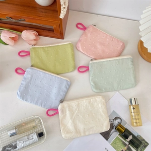 Macro shot of Swiss dot fabric cosmetic bags in pastel colors with woven zip pullers