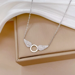 Detail of silver titanium steel necklace with sparkling wings on a brown jewelry box