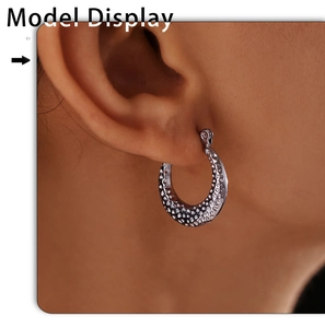 Close-up of C-shaped silver earrings with hammered texture on a female model