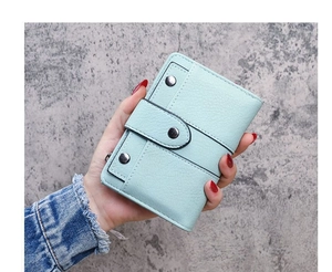 Detail of light blue lychee pattern leather wallet featuring three decorative metal studs