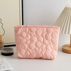 Dettaglio della borsa cosmetica trapuntata rosa con fiori su scrivania elegante