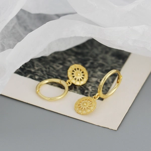 Detail view of gold S925 sterling silver hoop earrings with sunburst compass pendants
