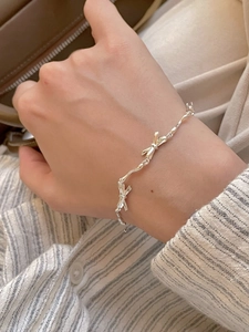 Close-up of minimalist S925 silver bow bracelet on wrist with elegant metallic texture