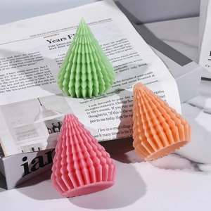 Three faceted Christmas tree candles in green, pink, and orange for home decoration