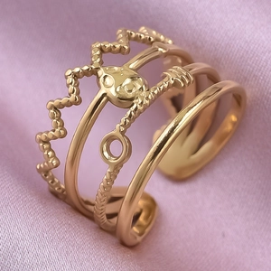 Detail of layered gold adjustable ring with crown and twisted design on pink satin