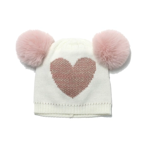 Cute kids' knit hat in cream with pink hearts and double faux fur pom-poms on white background