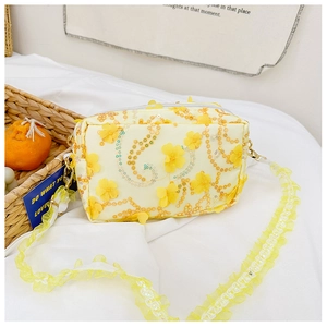 Detailed macro view of floral stitching and lace strap on yellow sequin crossbody bag