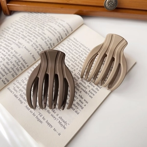 Matte large shark hair claws in brown and khaki displayed on an open vintage book