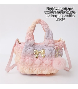 Close-up of quilted gradient crossbody bag with golden bow hardware and pink fur pompom