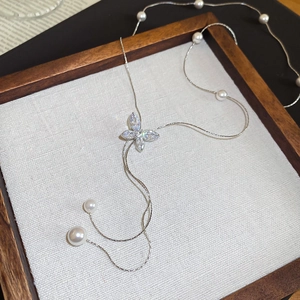 Close-up of elegant silver necklace featuring a zircon butterfly and white pearls