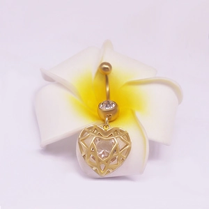 Piercing de nombril doré avec pendentif cœur et gemme claire sur une fleur frangipanier
