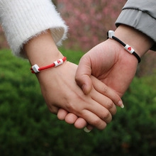 Close-up of magnetic matching bracelets for couples in red and black woven rope with heart charms