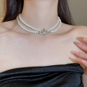 Detail of double-layer pearl necklace with a silver crystal-studded Saturn orb pendant