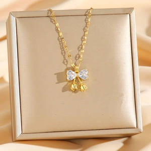 Gold titanium bow necklace with heart zircon and tulip pendants on silk display
