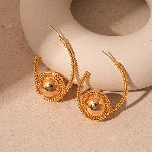 Detail of gold spiral wire wrapped hoop earrings with polished metal ball accents