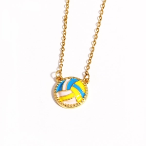 Detailed view of volleyball pendant necklace with blue, yellow and white enamel in gold finish