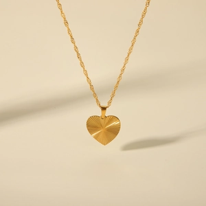 Close-up of gold heart pendant necklace featuring elegant sunburst textured metal design