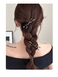 Detail showing two leopard print bow hair clips styled on a woman's braided hairstyle