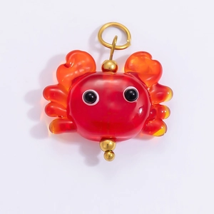 Macro detail of red translucent crab pendant with 18k gold plated metal connector