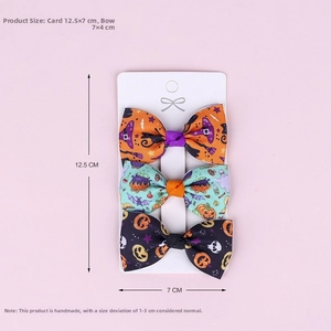 Close-up of three Halloween bow clips with pumpkin and ghost prints on a paper card