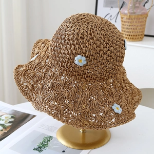 Détail d'un chapeau de paille marron tissé main avec fleurs tricotées sur support en métal