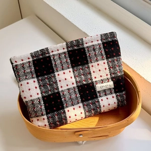 Macro detail of plaid tweed makeup bag with red dots and H & R woven label in a basket