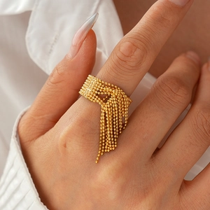 Detail des goldenen Quastenrings mit Perlenketten und Vintage-Metalltextur