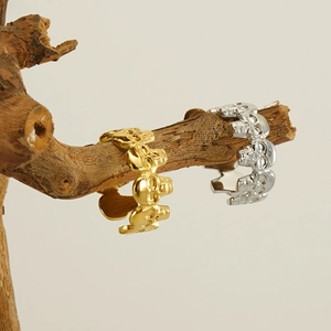 Detail of gold and silver skull rings displayed on a natural wooden branch