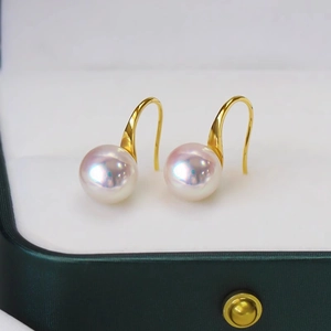 Elegant white Mabe pearl earrings with golden hooks on dark green jewelry box lining