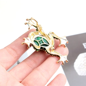 Detailed back view of a gold-tone frog brooch showing the green gemstone and secure pin clasp