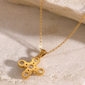 Macro shot of gold hollow cross star pendant on a minimalist chain with natural stone