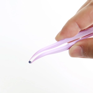 Pink nylon tweezers picking up a small bead for diamond painting and DIY crafts
