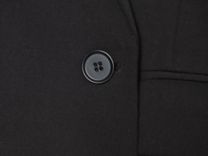 Détail macro du tissage sergé et d'un bouton à quatre trous sur une veste noire