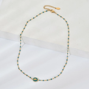 Détail du collier en acier doré avec perles turquoise et pendentif poisson émaillé bleu