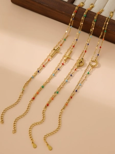 Detail of 18K gold-plated bracelets featuring colorful beads and horseshoe cross charms
