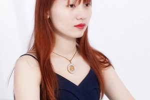 Detail of gold tree of life pendant necklace with white enamel inlay on a female model