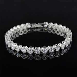 Macro view of silver tennis bracelet with cubic zirconia reflecting on black surface