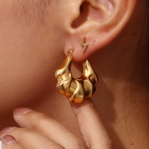 Polished 18K gold-plated wave hoop earrings with mirror finish on female model