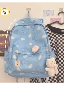 Light blue canvas backpack with cute white bear prints and plush pendants hanging on a wall