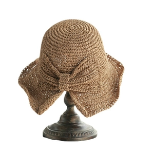 Sombrero de paja marrón con lazo grande sobre un soporte de exhibición retro